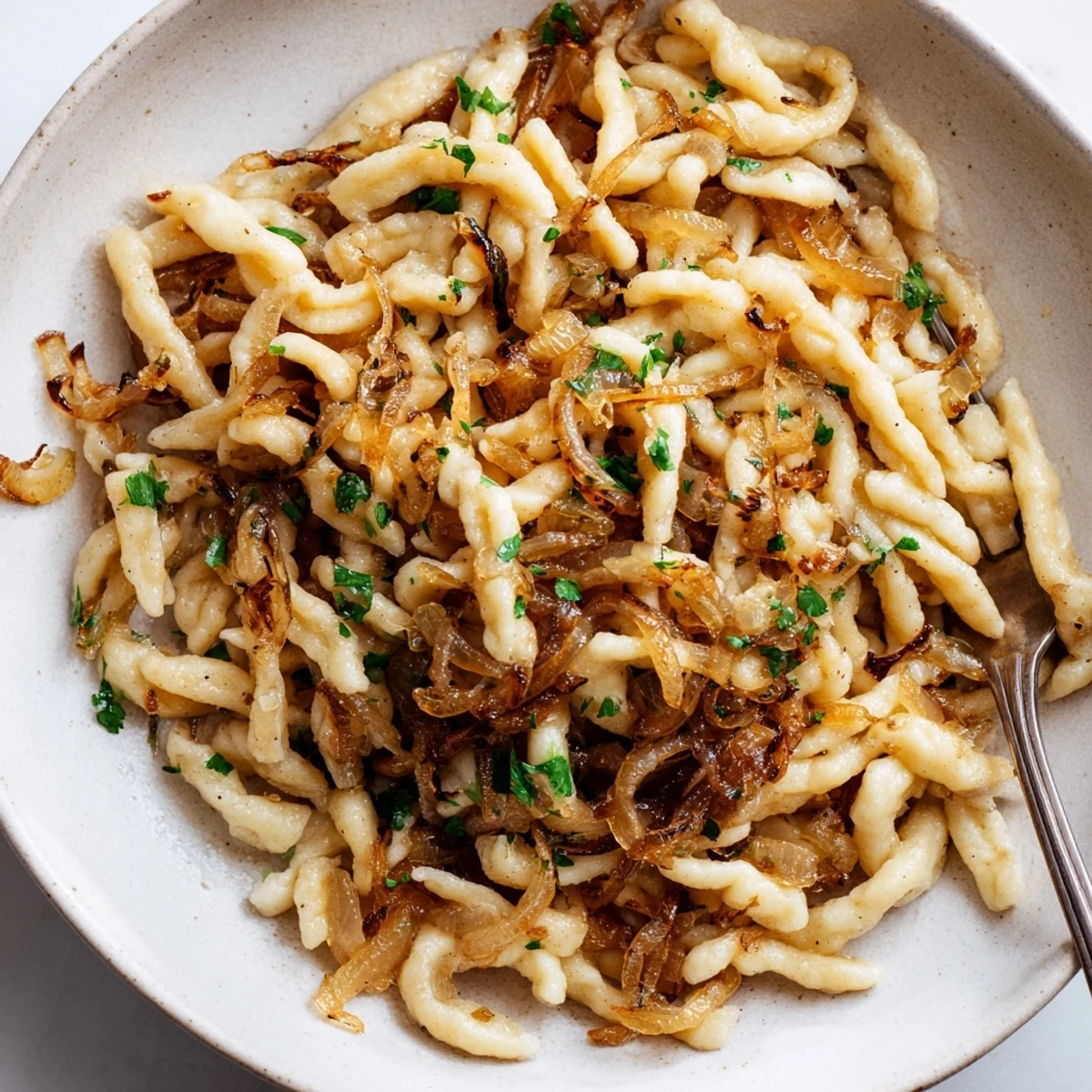 Schmackhafte Spaetzle mit karamellisierten Zwiebeln, ein Bissen deutscher Gemütlichkeit.