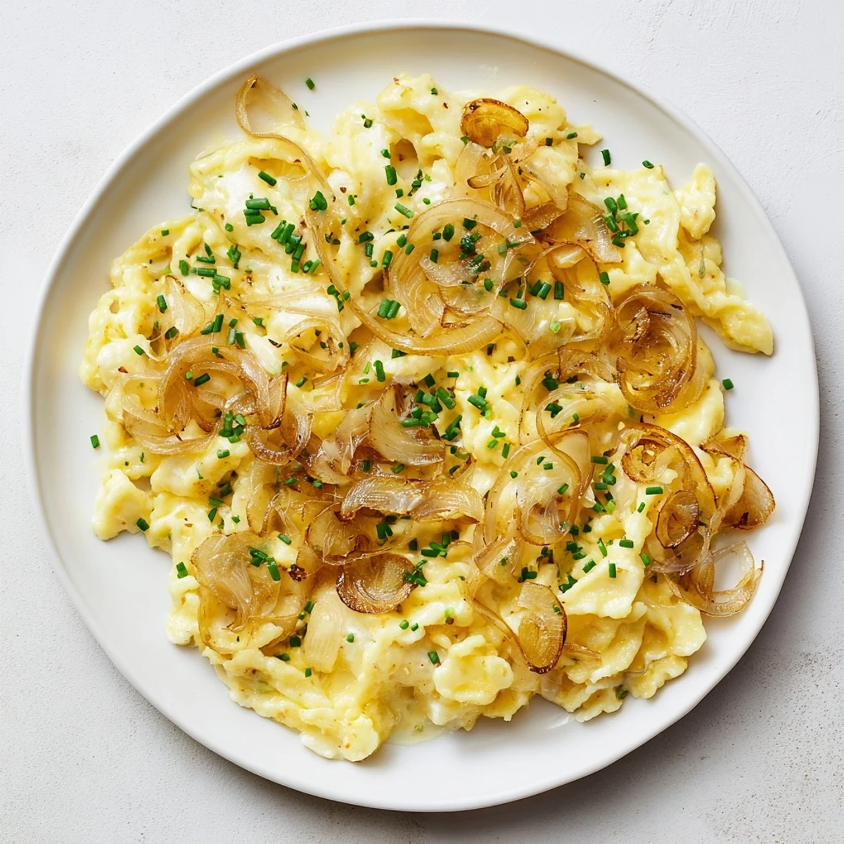Melted cheese coats perfect Käsespätzle, featuring caramelized onions and fresh parsley, a comforting German meal.