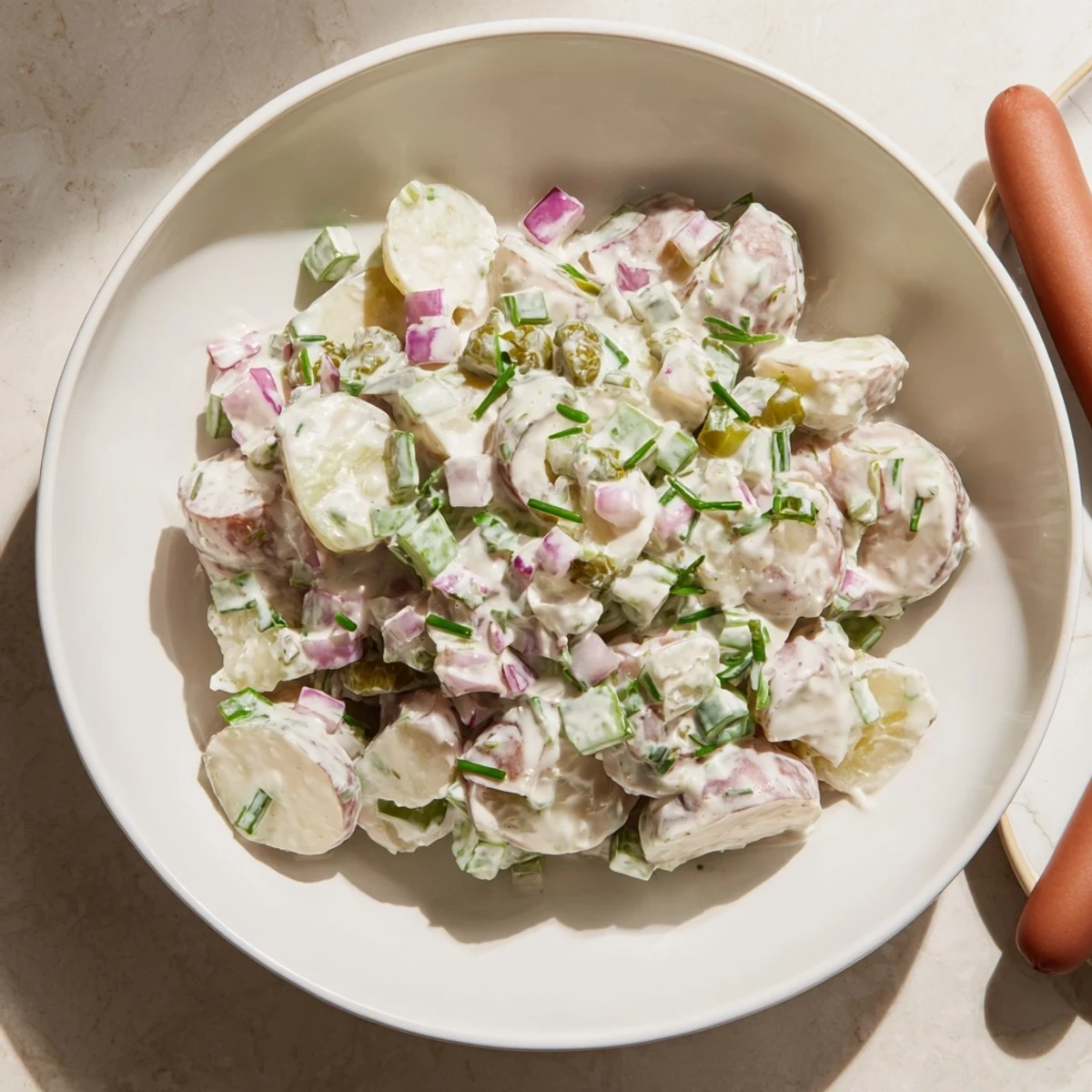 Savory German potato salad with sizzling sausages, a hearty meal served warm.