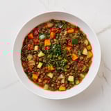 Steaming bowl of One-Pot Lentil & Vegetable Stew, seasoned with herbs for a flavorful, vegan dinner.