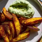 Close-up of crispy oven-baked potatoes, perfectly seasoned, served alongside fresh herb quark dip.