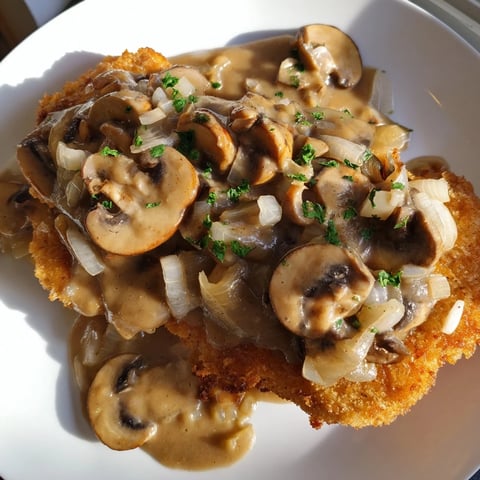 Crispy Hunters Schnitzel, topped with rich mushroom gravy, ready for a hearty German meal.