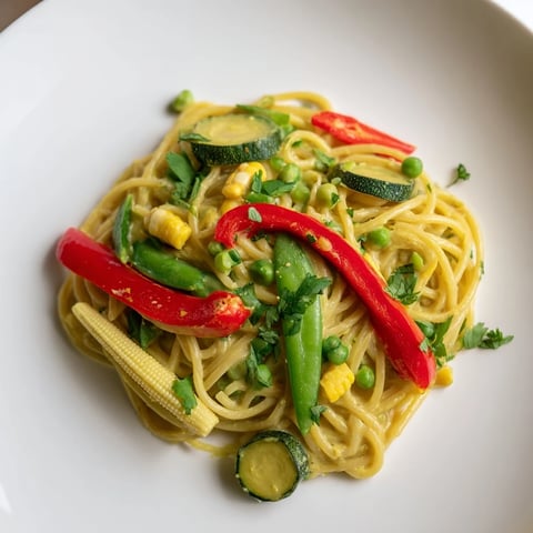 Creamy Thai Curry Pasta: a close-up shows tender pasta with vibrant green curry and veggies.