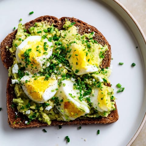 Close-up of freshly made avocado egg smash, garnished with chives; ideal for a light lunch.