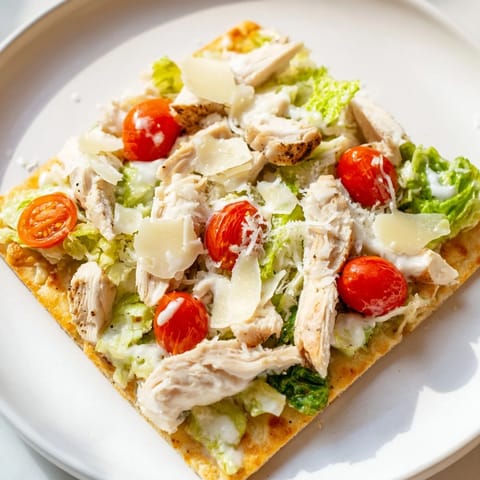 Golden Caesar Chicken Flatbread with fresh romaine, Parmesan cheese, and lemon wedges on the side.
