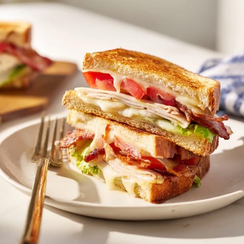 Sliced Turkey Club Grilled Cheese showing layers of bacon, turkey, and fresh lettuce.
