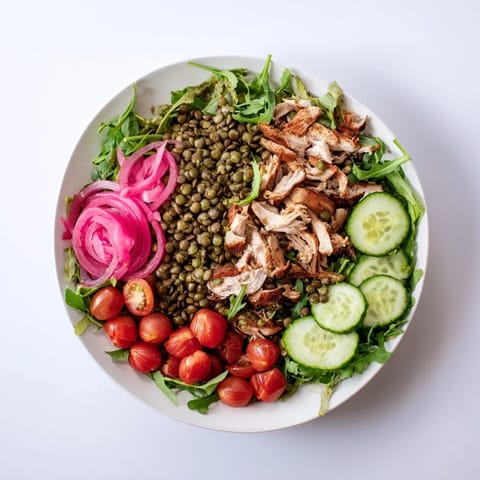 Lentil & Chicken Spring Salad mit knackigem Kürbis und würziger Senfdressing, auf frischem Rucola angerichtet.