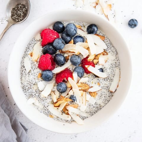 Ein Glas Poppy Seed Chia Pudding mit cremiger Textur, frischen Beeren und gehackten Mandeln.