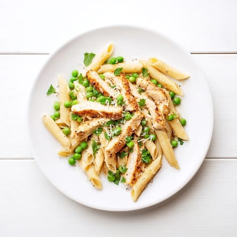 A close-up of Pea & Mint Chicken Pasta in a skillet, garnished with fresh mint and lemon zest.