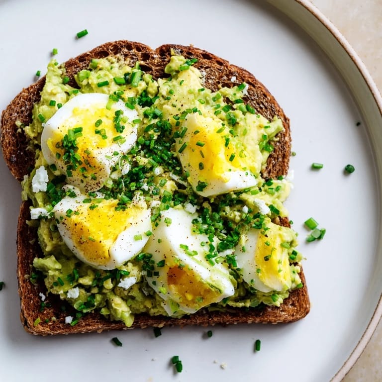 Close-up of freshly made avocado egg smash, garnished with chives; ideal for a light lunch.