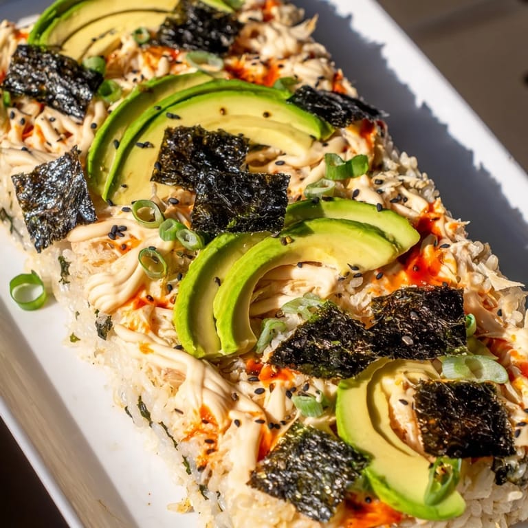 A close-up shot of baked Sushi Bake Casserole with toppings, ready for dipping in soy sauce.