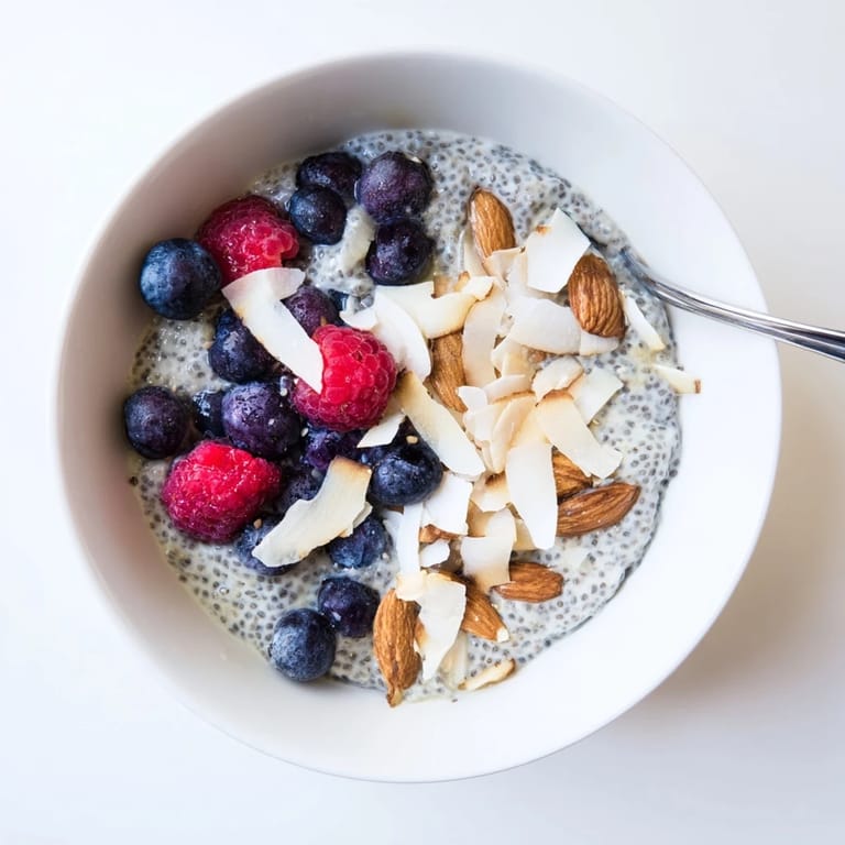 Poppy Seed Chia Pudding im Glas, serviert mit blauen Heidelbeeren und getoasteten Mandeln.