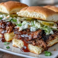 Zarte, rauchige Brisket-Scheiben auf weichen Slider-Brötchen mit würziger BBQ-Sauce und knackigem Krautsalat—perfekt für jede Feier.
