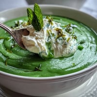 Eine leuchtend grüne Erbsensuppe mit luftigem Ricotta und frischem Minzöl.